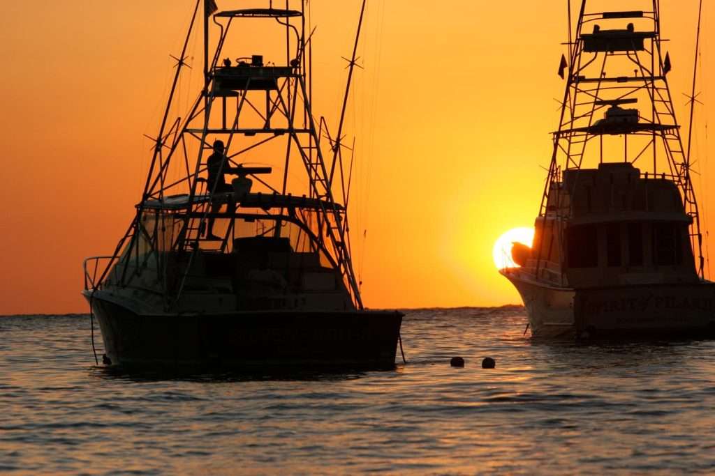 Offshore sportfishing charter boats silhouetted at sunset near Playa Carrillo Costa Rica from Ventanas del Mar