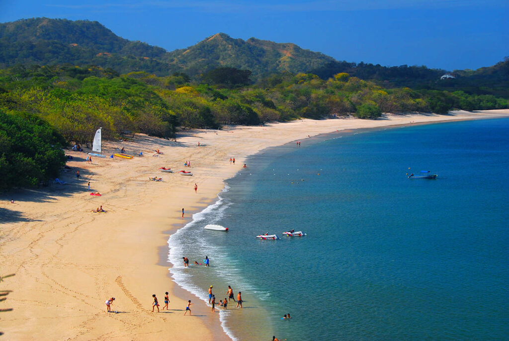 Crushed-shell shoreline and clear turquoise water at Playa Conchal, Guanacaste, Costa Rica, a calm family swimming beach